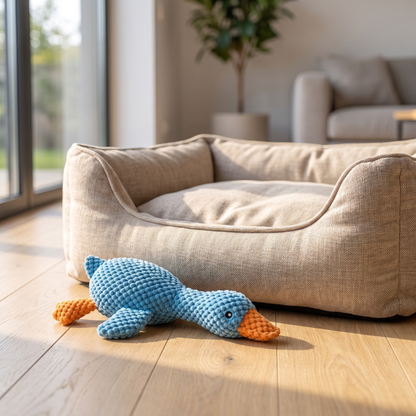 Tough-Bite Plush Goose on a wood floor beside a dog bed
